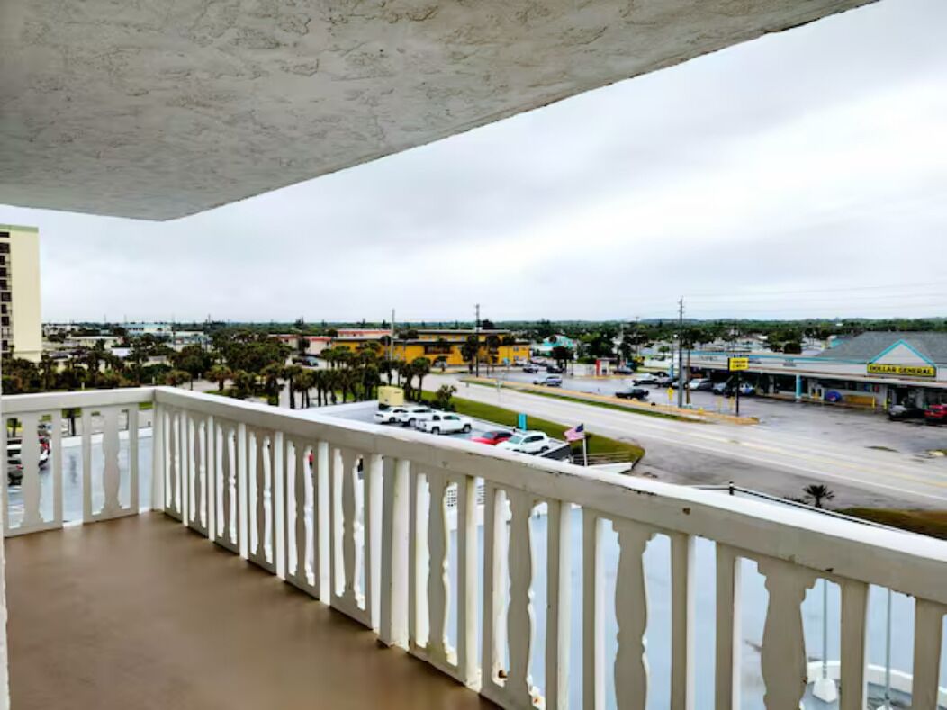 En balkong med utsikt över en stadsbild, inklusive en väg, byggnader och en bensinstation.