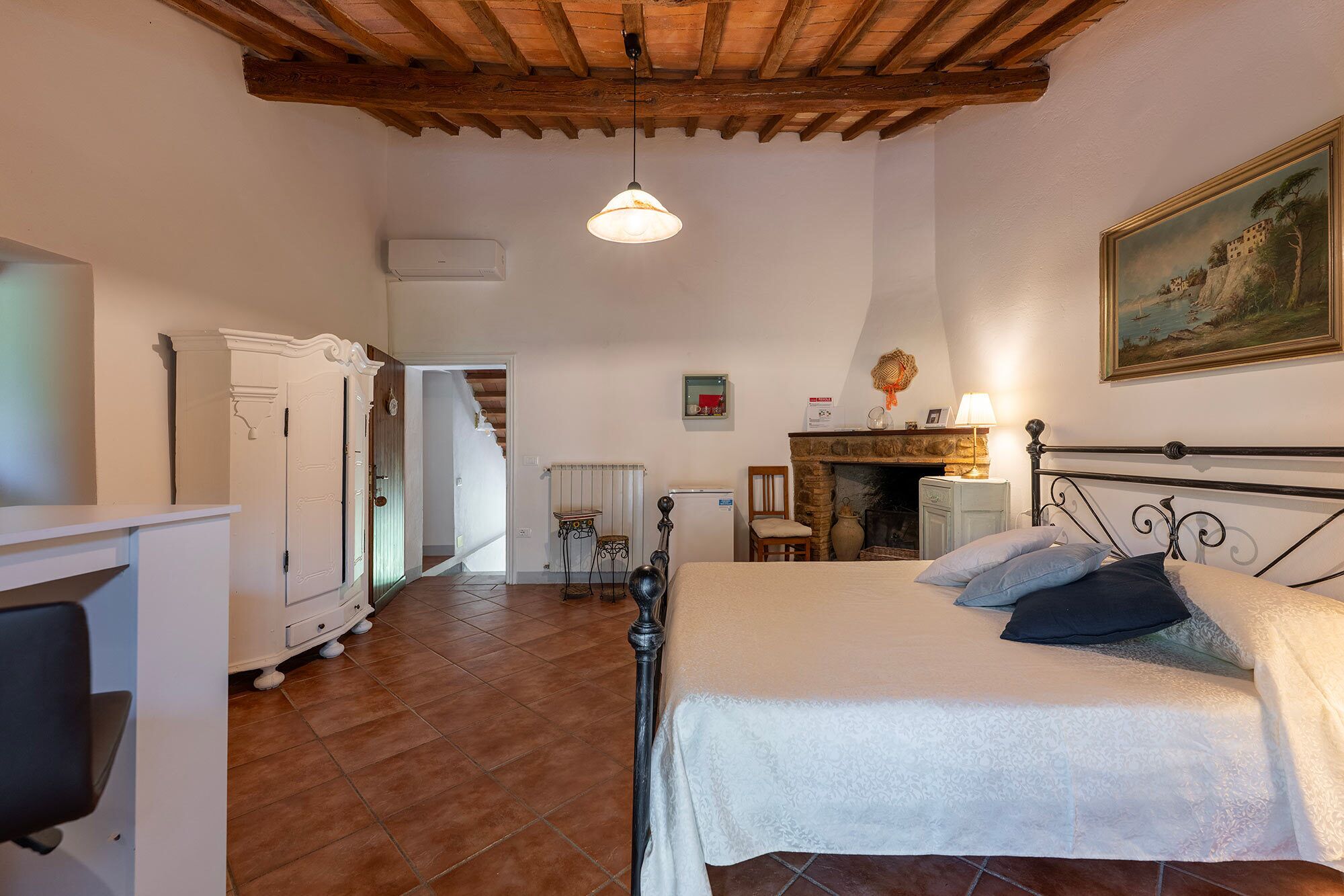 Une chambre à coucher avec un lit, une cheminée, un tableau et un plafond en bois.