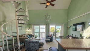 Amplia sala de estar con una escalera espiral, un comedor y una cocina con una isla grande.