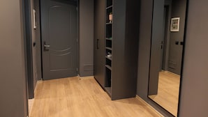 A hallway with a closed door, a mirrored wall, and a built-in shelving unit. - Hotel Bel Ami Tirana (Tirana)