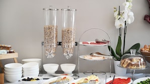 A buffet setup with food items, bowls, and a three-tiered serving tray. - Hotel Bel Ami Tirana (Tirana)