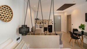 A modern living room with a sofa, a dining table with chairs, and a kitchen area in the background. - Deluxe family room in Naxos town (shared pool)  (Naxos)