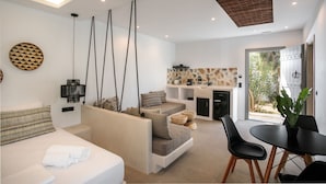 A modern living room with a sofa, a dining table, and a kitchen area. - Deluxe family room in Naxos town (shared pool)  (Naxos)