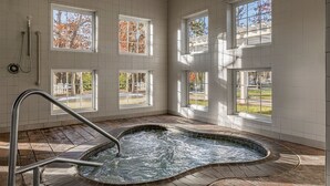Un área de spa con un jacuzzi, ventanas amplias y suelo de baldosas.