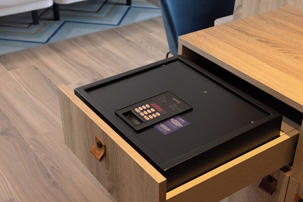 Un cajón de madera con un dispositivo electrónico negro, posiblemente una caja fuerte, encima.