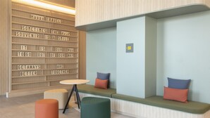 Un espace de détente moderne comprenant un banc, des poufs et un mur orné de citations inspirantes.