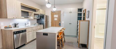 A modern kitchen with wooden cabinets, stainless steel appliances, and a central island with chairs.