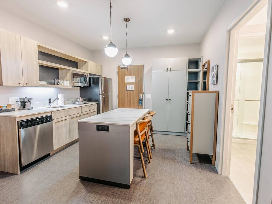 Una cocina moderna con armarios de madera, electrodomésticos de acero inoxidable y una isla central con sillas.