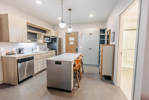 A modern kitchen with wooden cabinets, stainless steel appliances, and a central island with chairs.