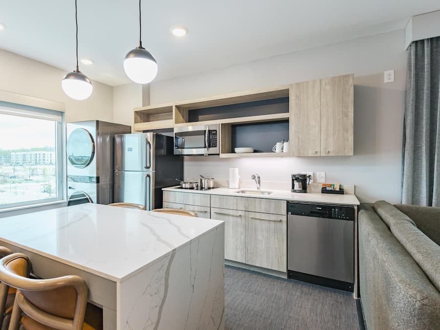 Une cuisine moderne dotée d’un îlot central, d’appareils électroménagers intégrés et offrant une vue sur la ville.
