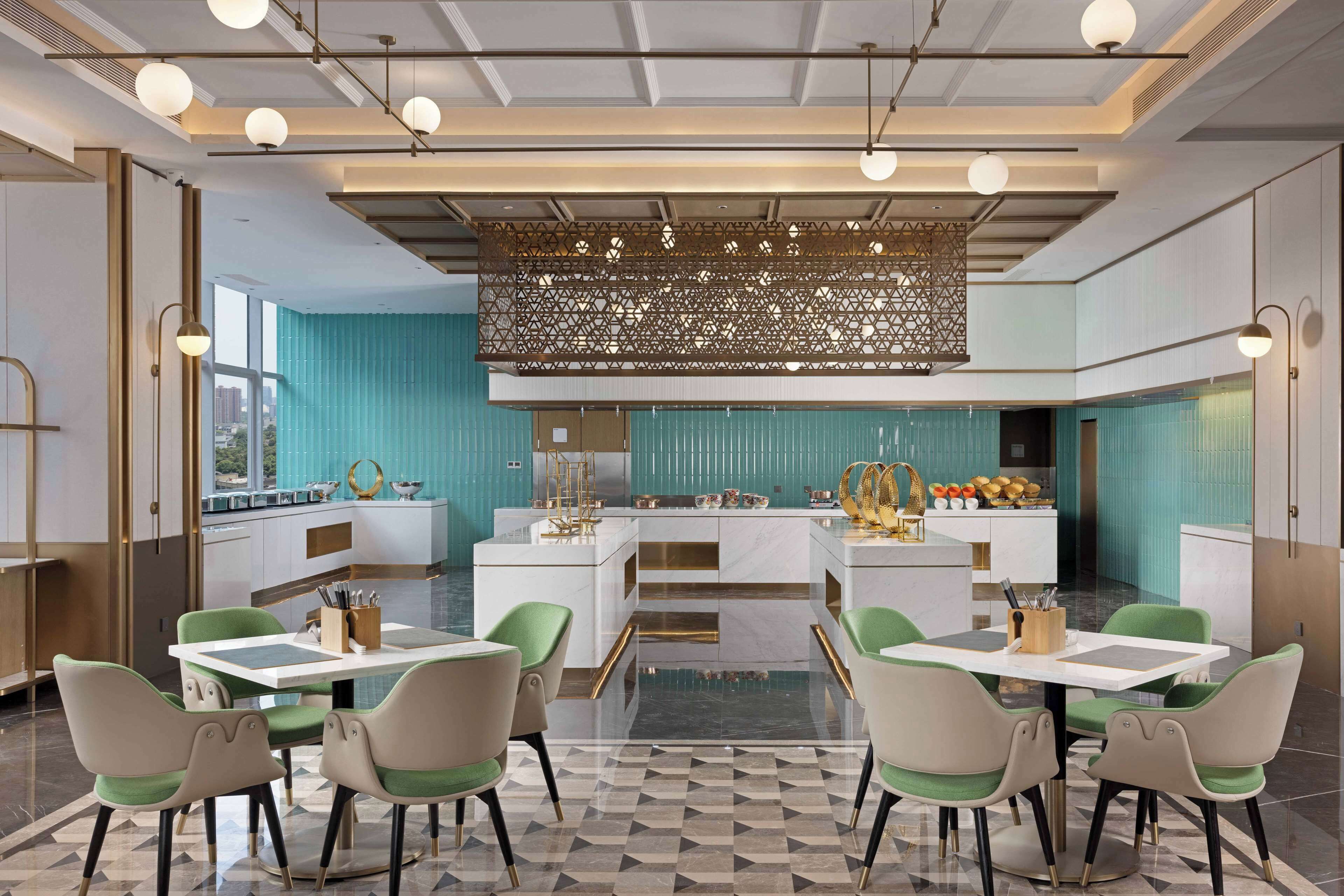 A modern kitchen with a central island, green chairs, and a patterned floor.