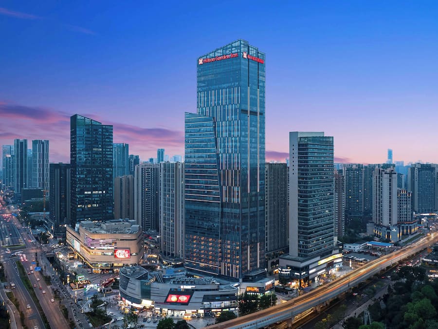 A high-rise hotel with a modern glass facade, surrounded by other tall buildings and busy streets.