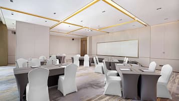 A conference room with a large table, white chairs, and a projector screen.