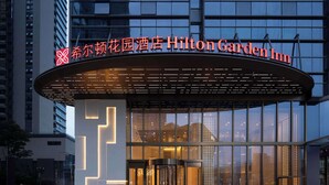 The exterior of the Hilton Garden Inn with a modern design, featuring large glass windows and a prominent entrance with revolving doors. - Hilton Garden Inn Chengdu Chenghua (Chengdu)