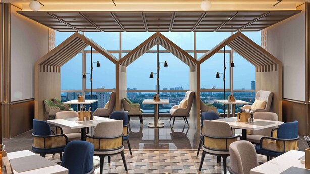 A modern restaurant with a terrace view, featuring geometric ceiling design and contemporary furniture. - Hilton Garden Inn Chengdu Chenghua (Chengdu)