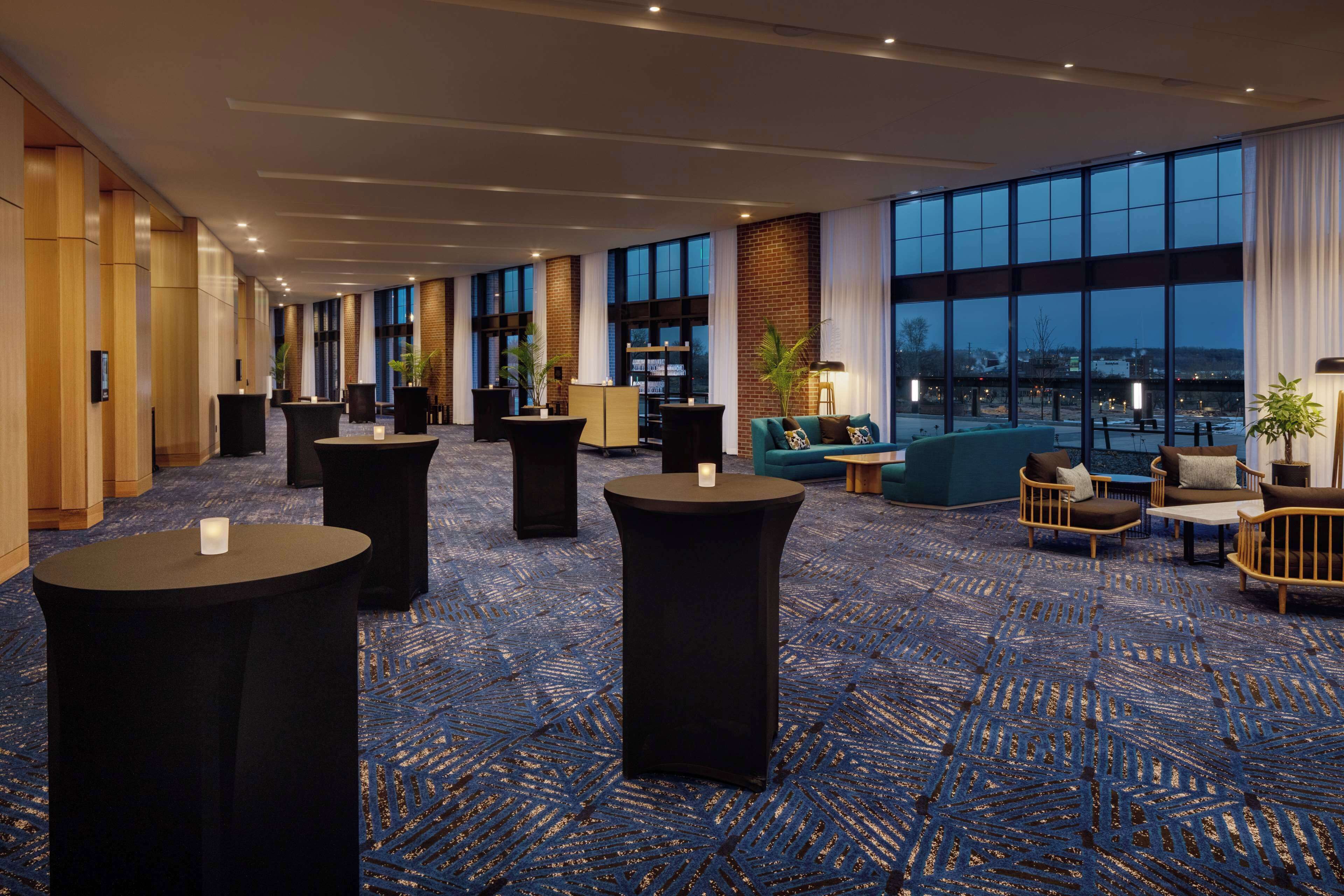 A spacious lobby with high ceilings, large windows, and a blue patterned carpet.