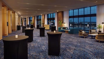 A spacious lobby with high ceilings, large windows, and a blue patterned carpet.