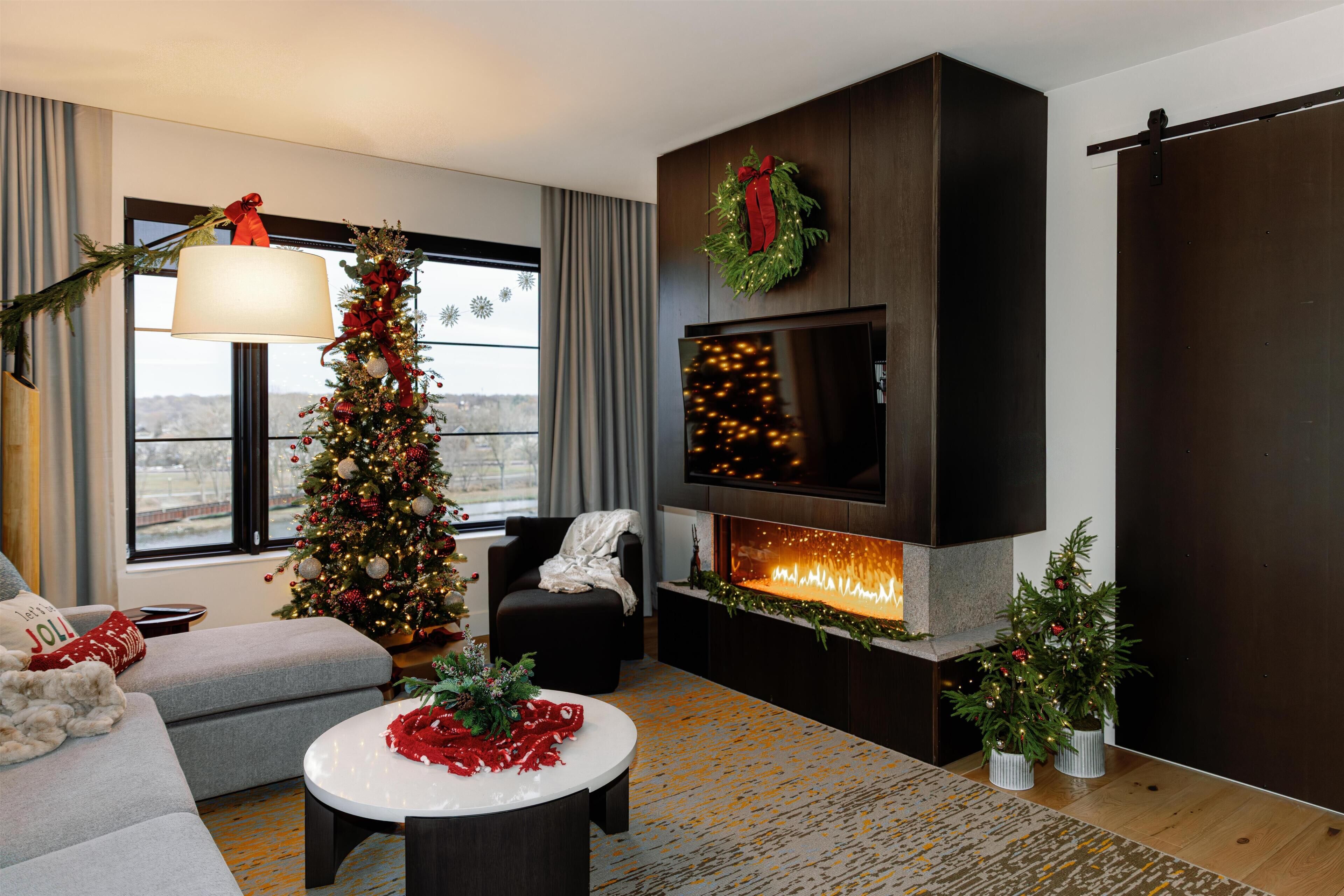 A modern living room with a fireplace, a Christmas tree, and a cozy seating area.