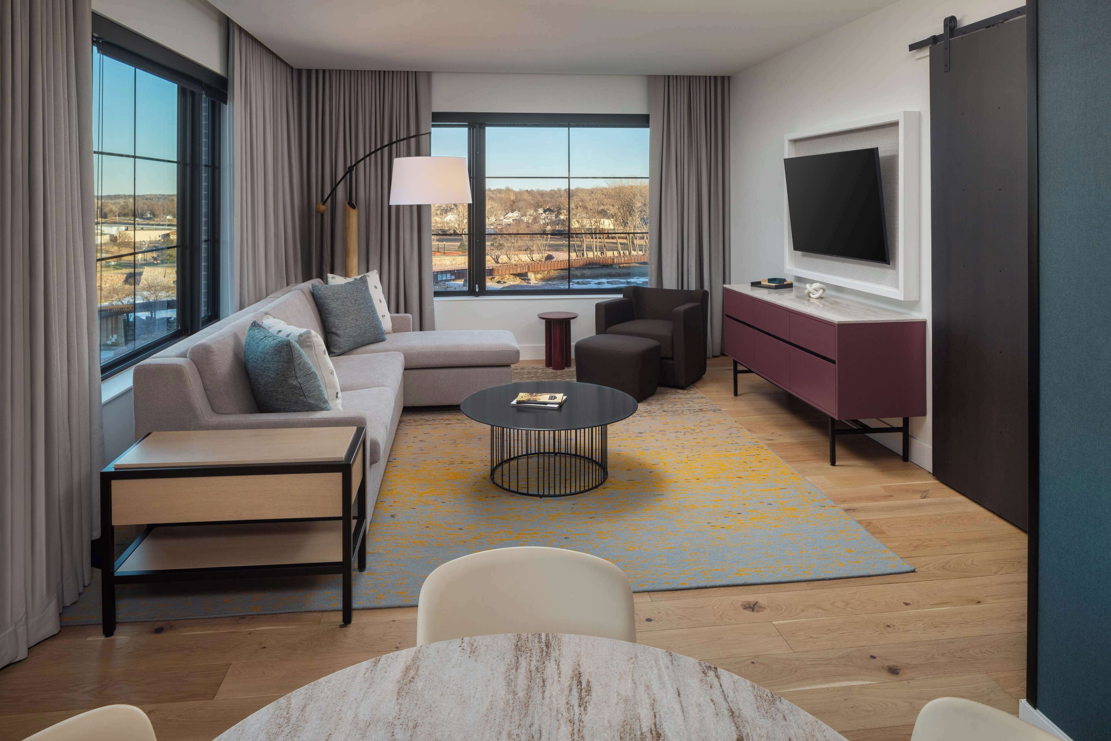 Un salon moderne avec un canapé, des fauteuils, une table basse et un téléviseur.