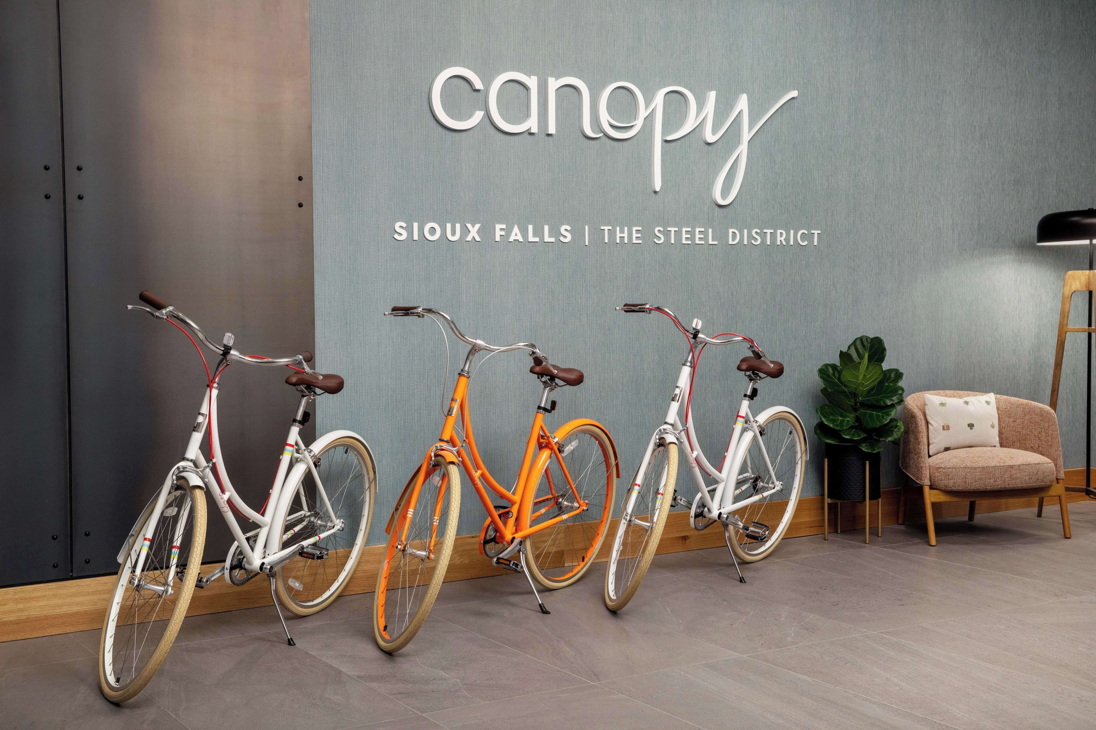 Three bicycles in a room with a wall displaying the text "canopy Sioux Falls | The Steel District".