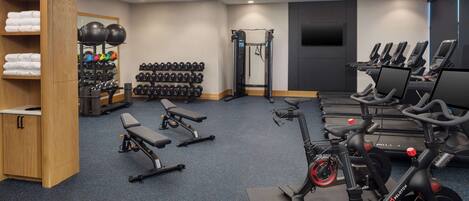 A gym with exercise equipment, a weight rack, and a bench.