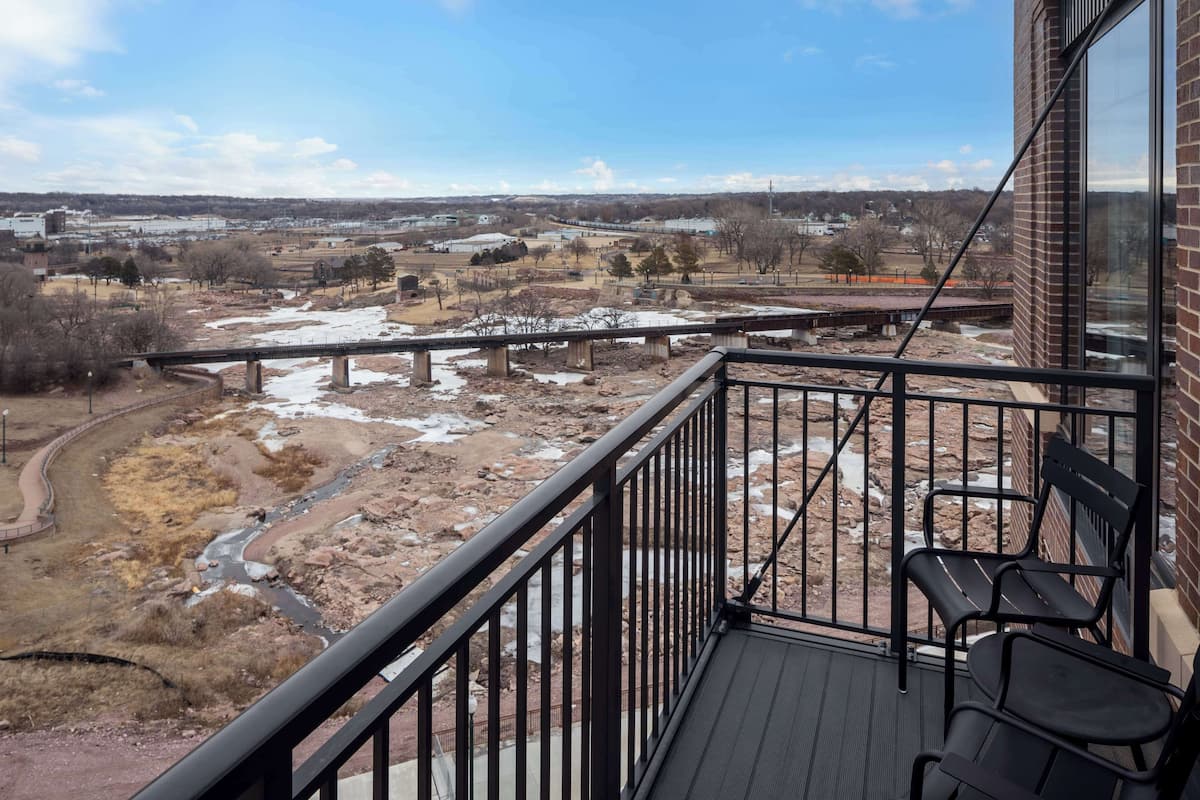 Een balkon met uitzicht op een rivier en het omliggende landschap.