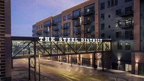 A modern building with a sign reading "THE STEEL DISTRICT" and a covered walkway. - Canopy By Hilton Sioux Falls Downtown (Sioux Falls)