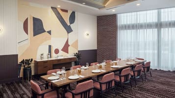 A conference room with a long table set for dining, surrounded by chairs.