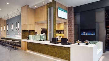 Una cafetería moderna con asientos y una pantalla digital que muestra opciones de menú.
