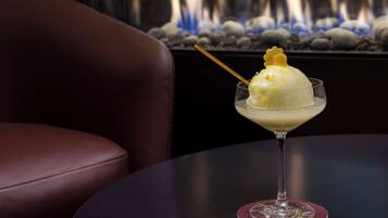 A dessert in a glass on a table with a chair in the foreground and a fire feature in the background.