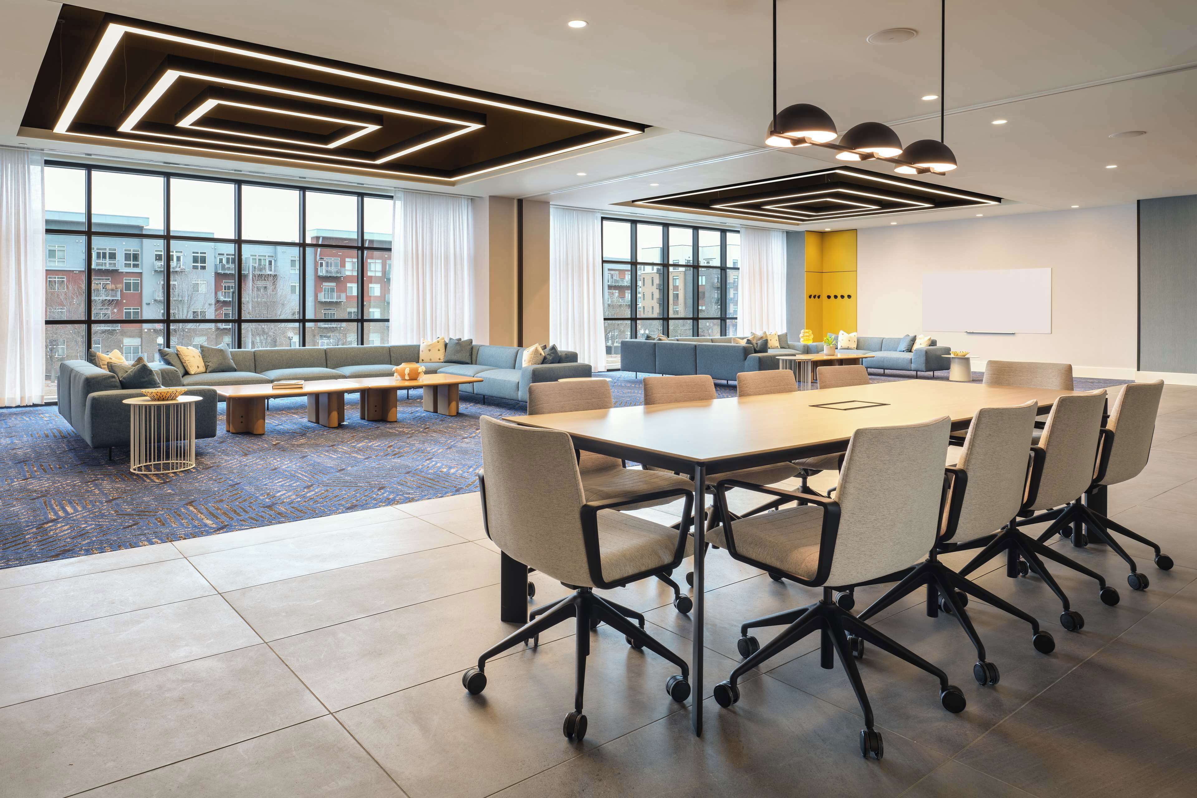 A modern conference room with a large table, multiple chairs, and sofas.