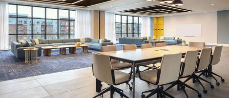 A modern conference room with a large table, multiple chairs, and sofas.