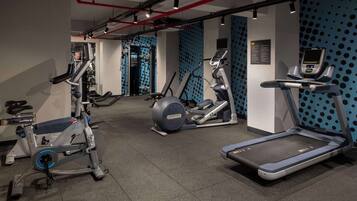 Un gimnasio con diferentes equipos de ejercicio, incluyendo cintas de correr, una elíptica y una bicicleta estática.