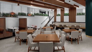 A modern indoor dining area with wooden tables and white chairs, a staircase, and green plants on the walls. - Embassy Suites By Hilton Madison Downtown (Madison)