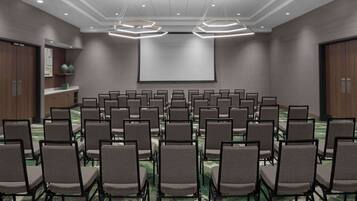 A conference room with rows of chairs, a large screen, and modern lighting fixtures.