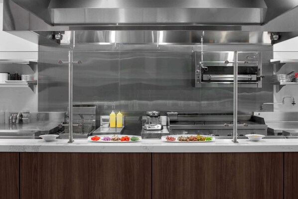 A modern kitchen with stainless steel appliances, including a built-in oven and a range hood. - Embassy Suites By Hilton Madison Downtown (Madison)