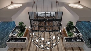 A modern interior with a spherical light fixture, wooden flooring, and two rectangular planters with water features. - Embassy Suites By Hilton Madison Downtown (Madison)