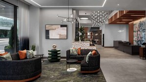 A modern lobby with a curved sofa set, a round coffee table, and a decorative floor lamp. - Embassy Suites By Hilton Madison Downtown (Madison)