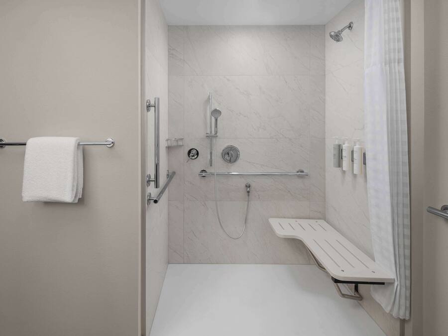 A modern bathroom with a shower, a bench, and a towel rack.