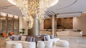 Un vestíbulo moderno con una zona de estar central, un mostrador de recepción y una lámpara decorativa.