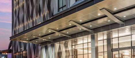 A modern hotel building with a geometric facade and illuminated windows.