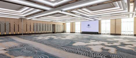 A spacious conference room with a patterned carpet, a large screen, and a modern ceiling design.