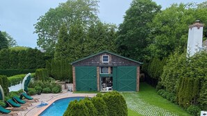 Une piscine avec des chaises longues, un abri de jardin et une végétation bien entretenue.