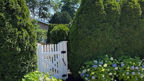 Un jardin avec un chemin de gravier, un banc en bois et une clôture blanche en bois.