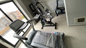 Un gimnasio con equipamiento de ejercicio, incluyendo una cinta de correr, una bicicleta estática y una máquina elíptica.