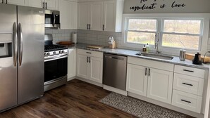 Una cocina moderna con armarios blancos, electrodomésticos de acero inoxidable y una ventana con vistas.