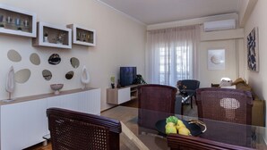 A modern living room with a glass dining table, wicker chairs, a TV, and decorative items on the walls. - Boutique Stylish 1 Bd Apt in Patisia (Athens)