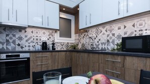 A modern kitchen with white cabinets, a microwave, and a dining area with a table set for two. - Boutique Stylish 1 Bd Apt in Patisia (Athens)
