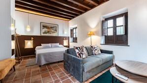 Una habitación con cama, sofá, una mesita y una ventana.