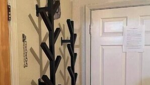 Ein Zimmer mit einer weißen Tür, einem Kleiderhaken mit mehreren Haken und einem kleinen Zettel an der Tür.